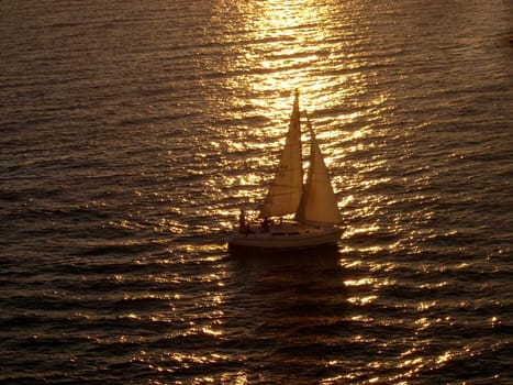 a sail boat arriving to port at sunset