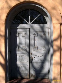 Church doors with shadows of a tree on them.