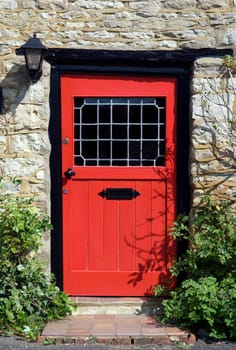 An old red door to the front of an English country cottage