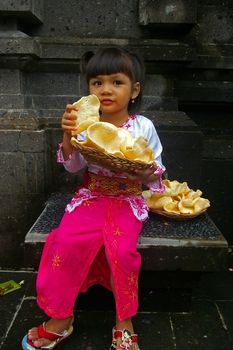 Bali (Indonesian) girl eating  Krupuk Udang(Prawn/Shrimp crackers), Jimbaran, Bali, Indonesia.