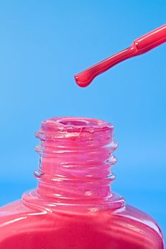 A close up of a bottle of nail varnish with a drip on the brush
