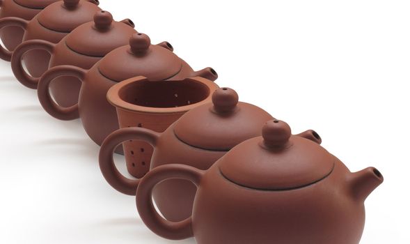 Clay teapots and tea strainer at row  on white background
