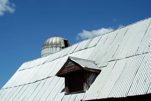 Barn window with silo against blue sky and clouds