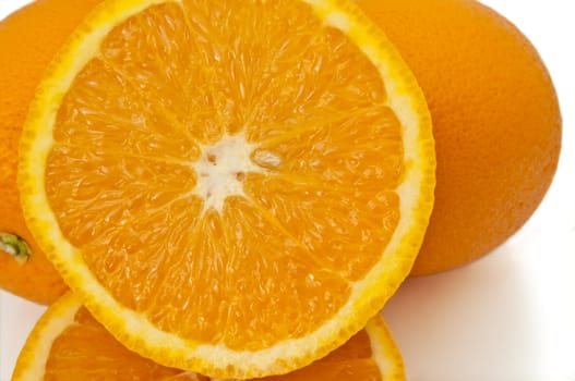 Close up capturing a selection of whole and halved fresh oranges over white.