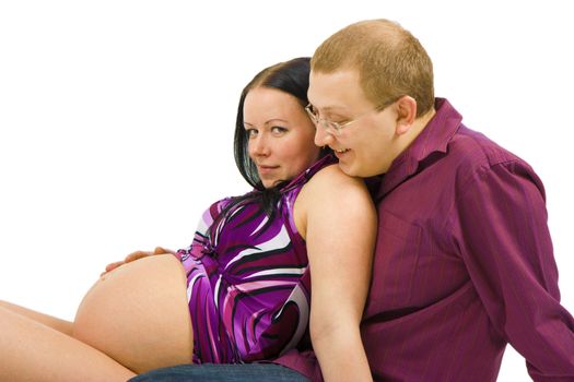 young couple awaiting the birth of a child sitting on the floor on a white background

