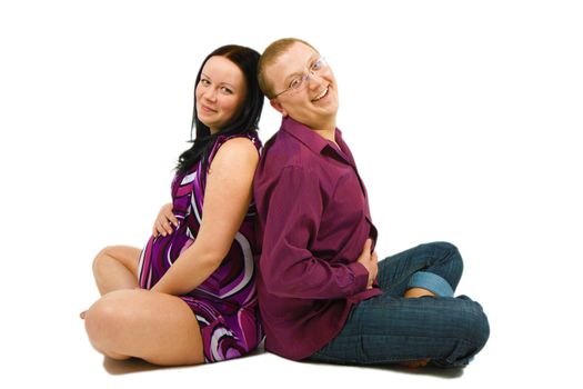 young couple awaiting the birth of a child sitting on the floor on a white background
