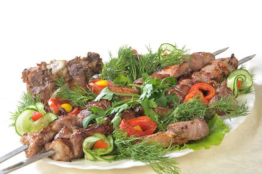 Hot dish of pieces of lamb on skewers in a dish served with vegetables.