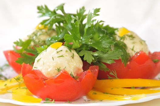 cold appetizer from red tomatoes with cheese marbles on a dish with cutting from yellow paprika and parsley