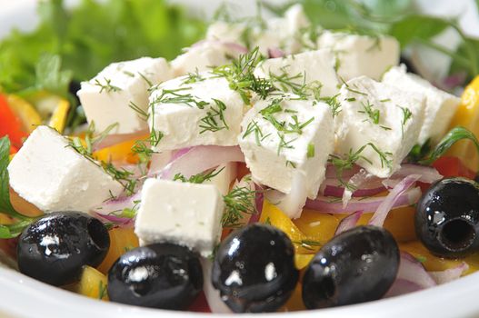 Close-up slices of cheese in a salad of feta cheese and diced vegetables