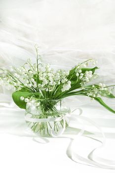 Lily of the valley in vase on white fabric background