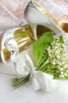 Lily of the valley and wedding shoes on white fabric