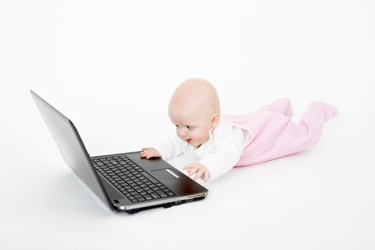 Baby playing with laptop on white background
