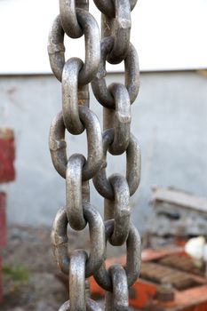 Vertical detail shot of heavy chain link on a construction site.