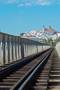 Railroad track bridge leading to a scenic old town