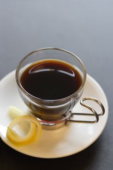 Image of a coffee with cup and saucer and lemon rind. Shallow depth of field.
