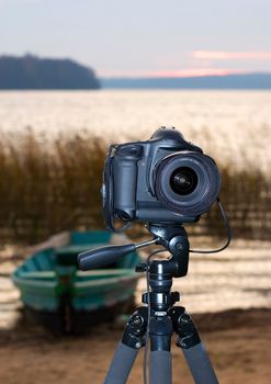 camera on tripod lake boat sunset