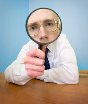 Man with a magnifier in a hand on a workplace