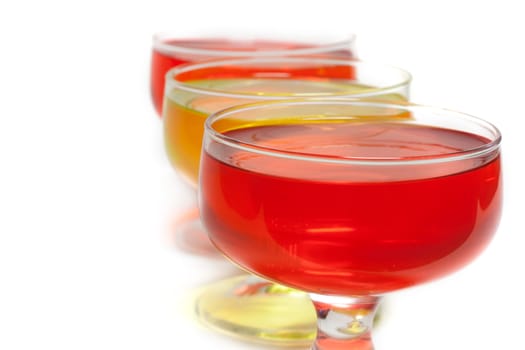 Yellow, red jelly in transparent glass stand on white background inline