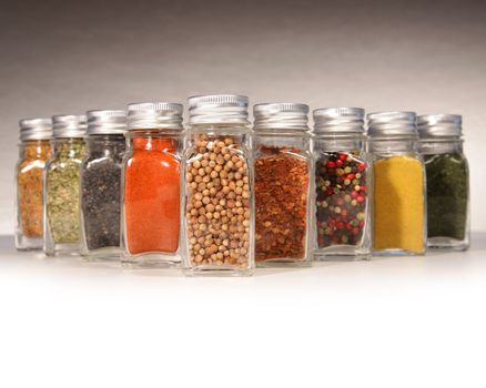Bottles of colorful spices with grey background