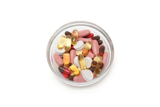 Multicolored tablets and capsules in transparent glass plate insulated on white background