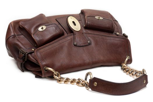 Beautiful brown leather feminine bag with golden chain-handle and lock insulated on white background