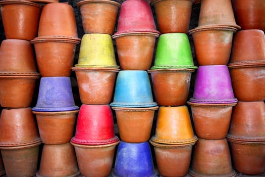 A background of red clay pots with some colored pots in them, for gardening.