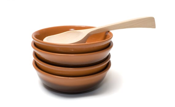 Pile of ceramic plates and wooden spoon on a white background.