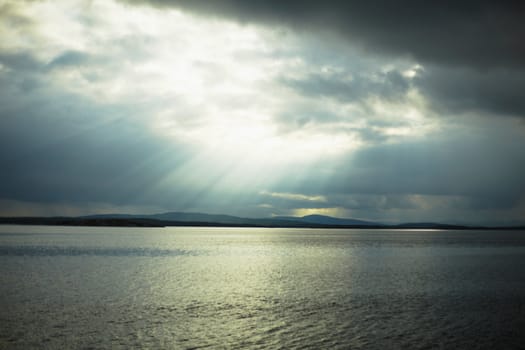 Evening landscape with northern sea and sun beams