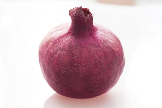 Fresh whole pomegranate on white table.