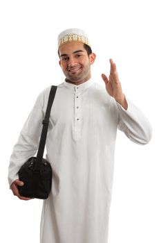 A man wearing a beautiful embroidered robe, thobe, kurta outfit fastened with ruby buttons and wearing a decorative topi hat.  He is waving in a friendly manner.  White background.