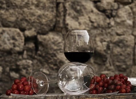 A glass of red vintage wine and some red grapes on a table