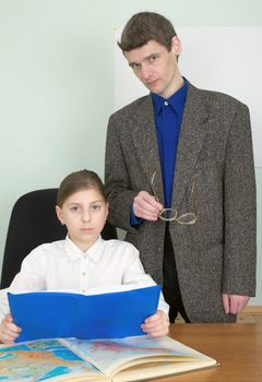 Tutor and schoolgirl with book and geographical atlas