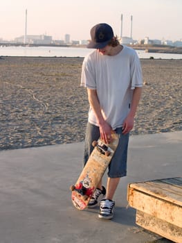 Teenager walking with skateboard in urban area