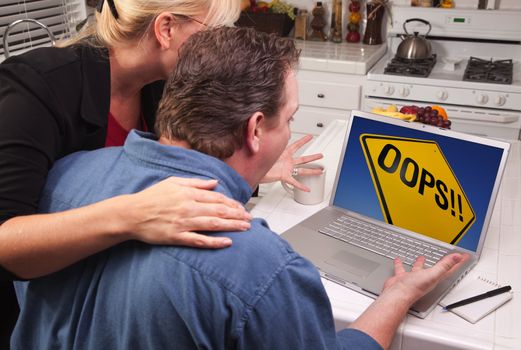 Couple In Kitchen Using Laptop with Yellow Oops Road Sign on the Screen.