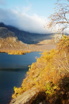 Coast mountain lake among the autumn forest