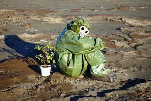 A man in a chemical suit and a houseplant in the desert