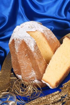 Christmas composition with Pandoro the golden cake of Verona two glasses of spumante and some ornaments over a blue background