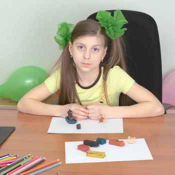 Girl sitting at a table with plasticine in hands