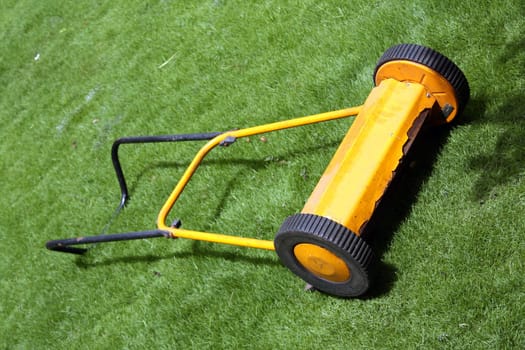 A yellow lawnmower on green grass.