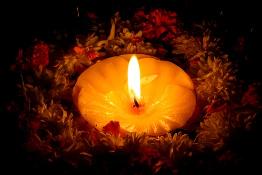 A holy candle surrounded by flowers for traditional Diwali festival rituals.