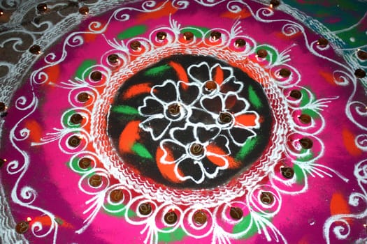 Lamps lit up in a traditional religious design made of colorful powder called "Rangoli", during Diwali festival in India.