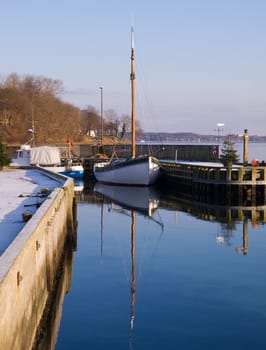 Reflection of a beautiful vintage classical wooden sail boat in a marina