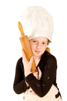 young cook wearing a chefs hat is holding a woorden rolling pin isolated on white