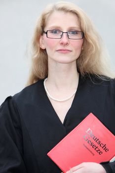 Young lawyer with the law book looks resolutely into the camera direction
 