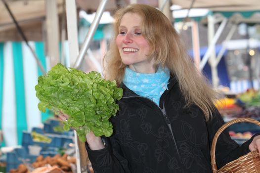 Woman at the market with a salad in his hand and smiling
