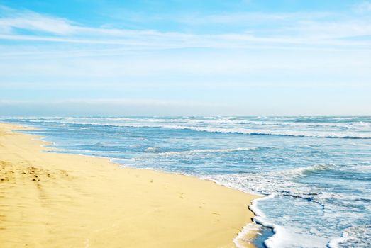 Beach in San Francisco California with waves coming to the sand and blue sky background.