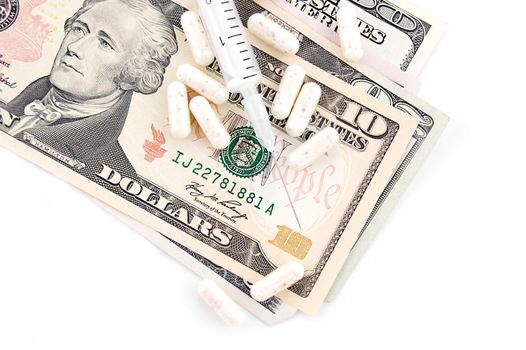 Medicine capsules and syringe on dollar bills