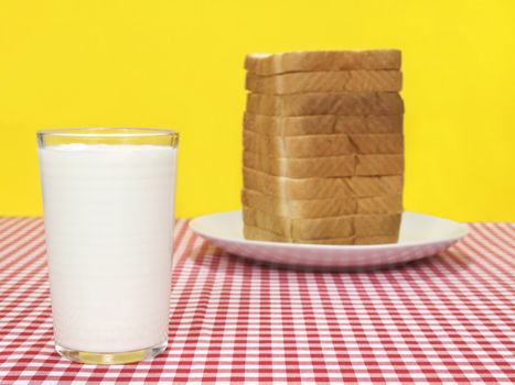 A glass of milk and a sliced loaf of bread.