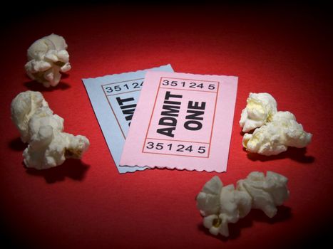 Close up shot of two generic admission tickets and some popcorns arround.