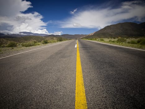 A desert road by the mountains surrounded by colorful nature.